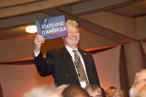 Walt Copan holds up a card that says Etats-Unis D'Amerique